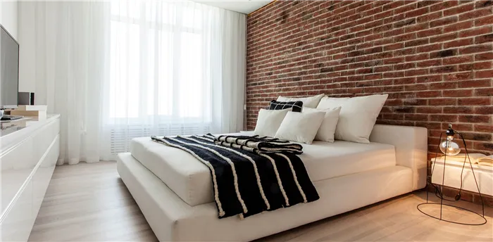 Кирпичные стены прекрасно гармонируют с белыми кроватями